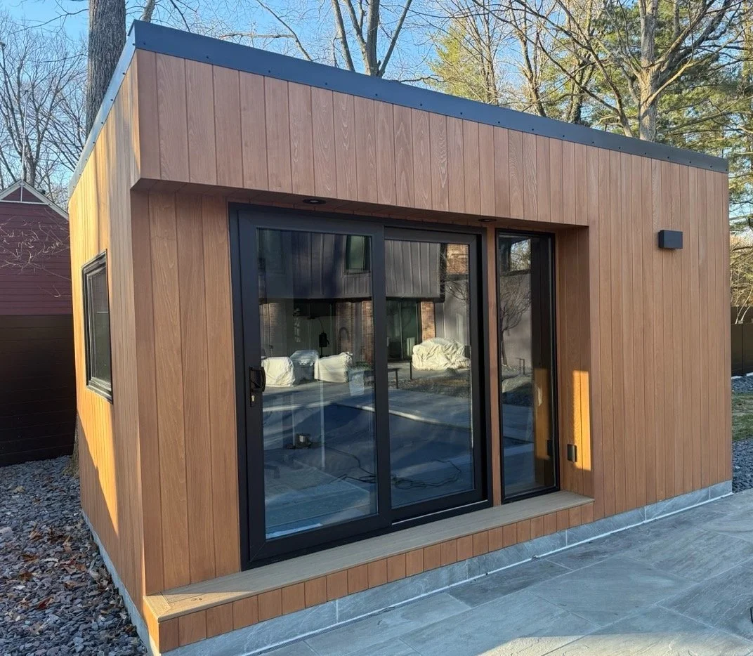 Cedar-clad backyard studio shed with large windows